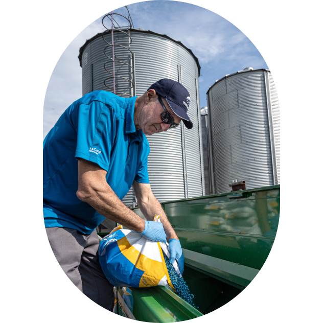 A Maizex expert pours a bag of seeds into a seeder.