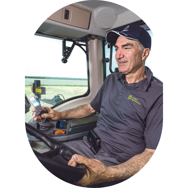 Un producteur conduit son tracteur dans un champ de grandes cultures. 