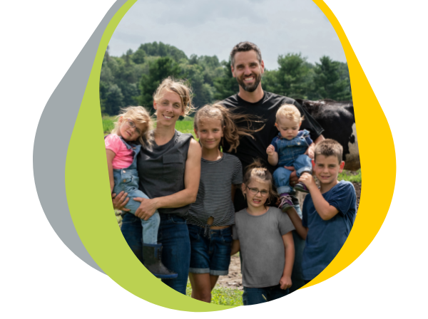 Portrait of a dairy farming family outdoors, with a grazing cow in the background.
