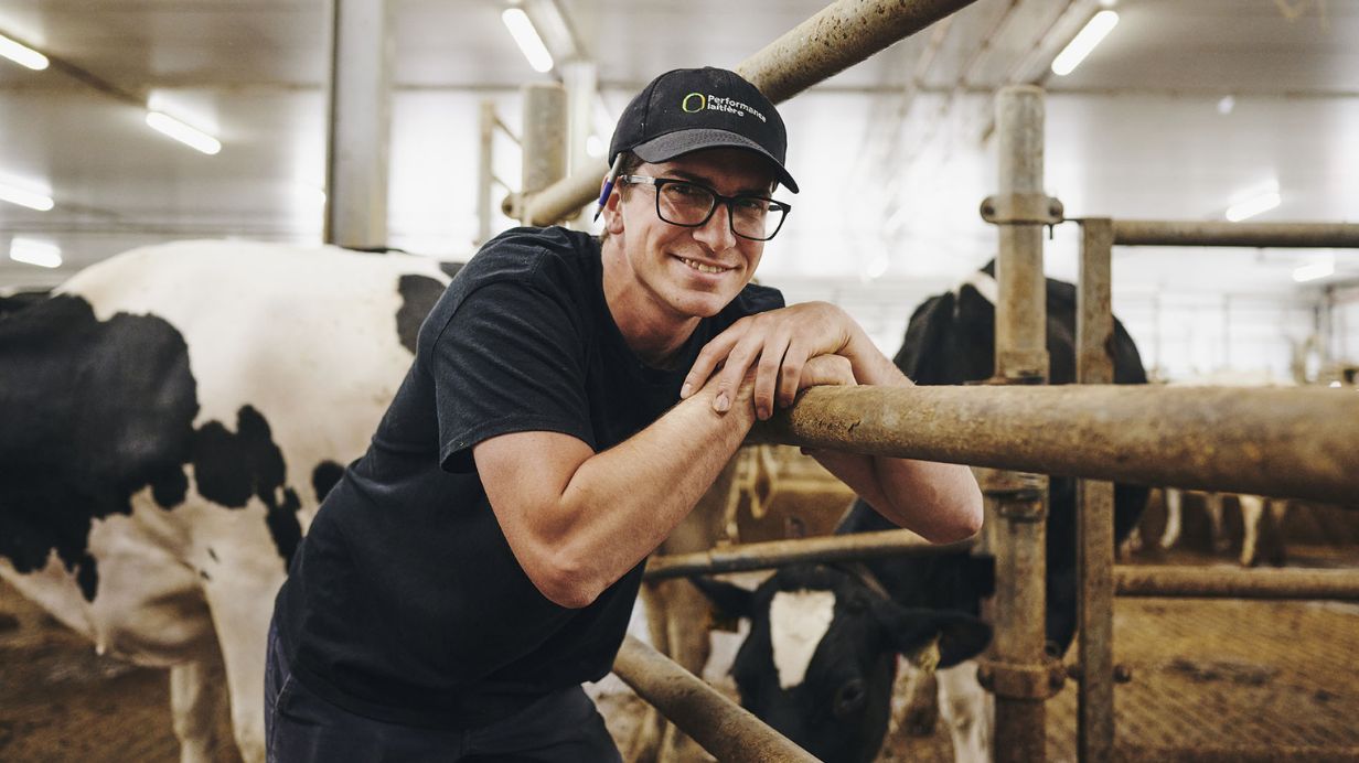 Un récipiendaire du concours Performance laitière pose dans son étable avec ses vaches.
