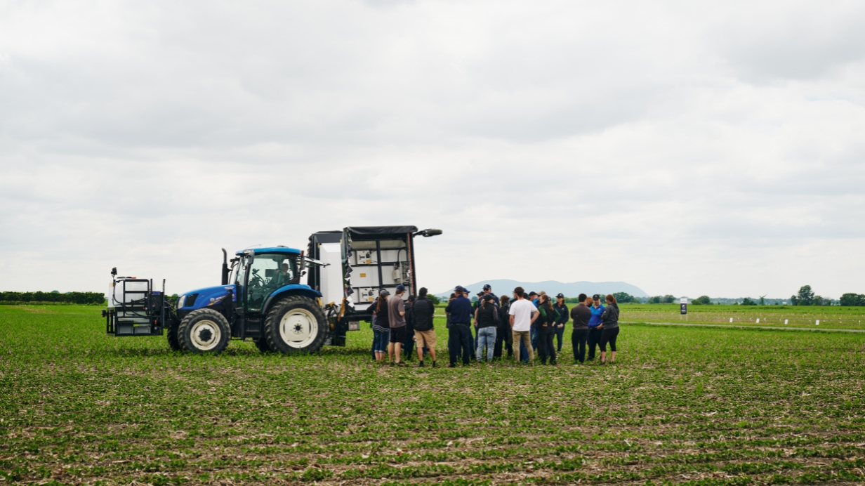  Des experts-conseils observent le pulvérisateur intelligent dans un champ de la ferme de recherche. 