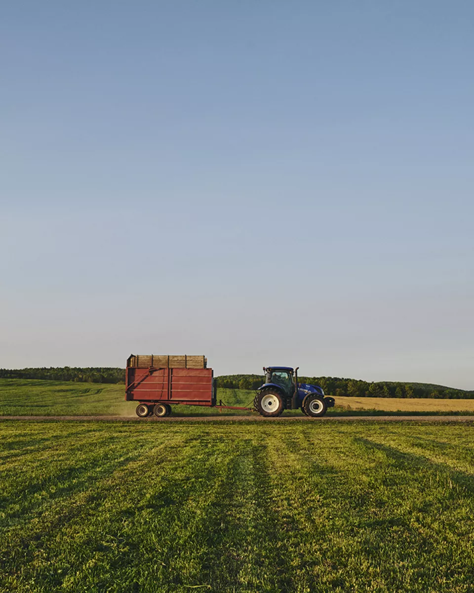 Un tracteur bleu tire une remorque rouge